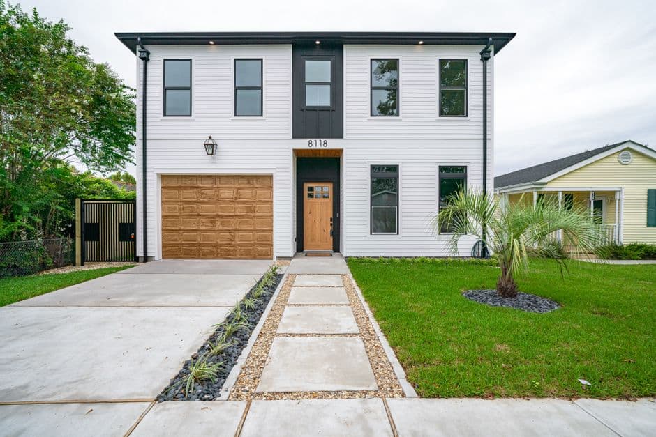 Newly built two-story white home with a palm tree in a Southern coastal neighborhood