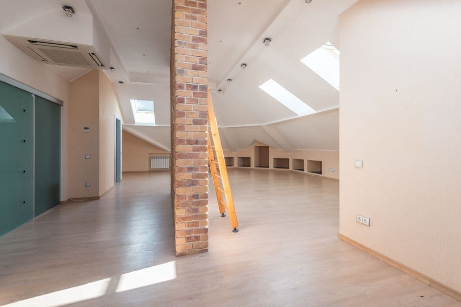 Open finished attic space with sloped ceilings and skylights ready for insulation